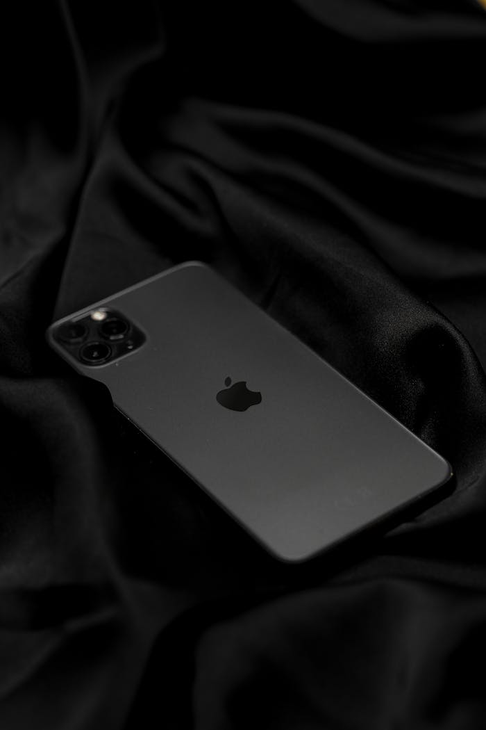 Stylish black smartphone set against smooth, luxurious black fabric. Perfect for showcasing technology and elegance.